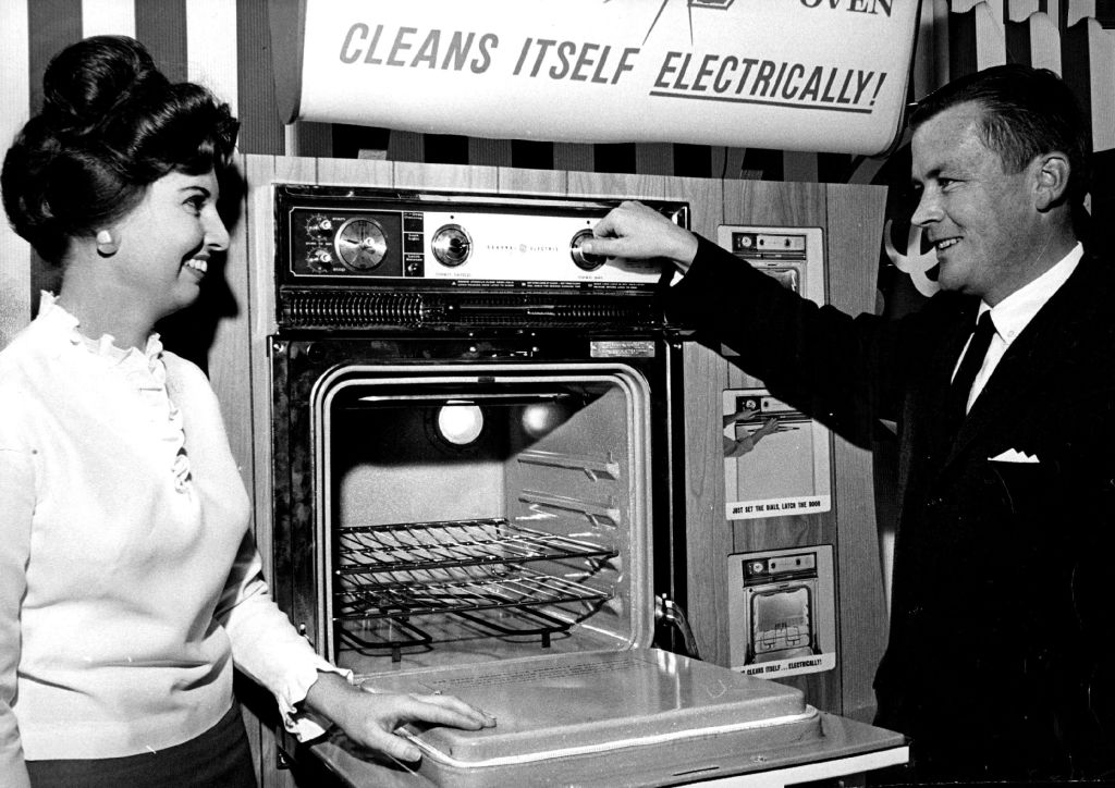 man showing off new oven to woman